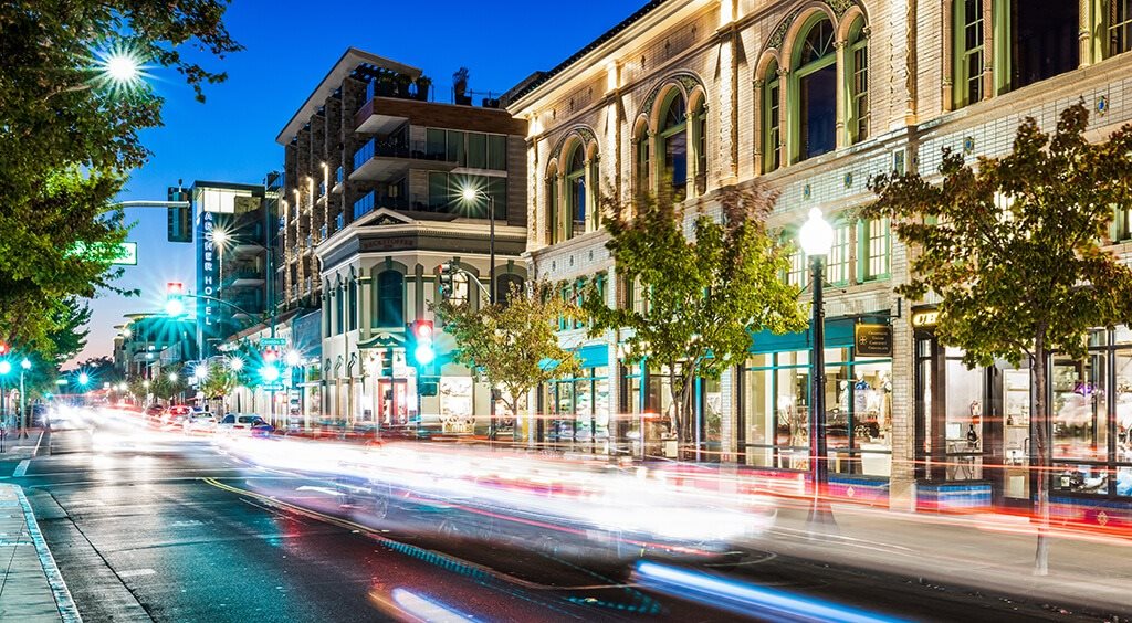 A long exposure shot of a city street at night with light trails from moving vehicles